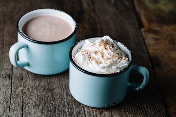 Two cups of hot cocoa on rustic wooden surface