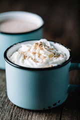 Two cups of hot cocoa on rustic wooden surface