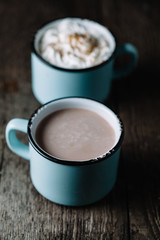 Two cups of hot cocoa on rustic wooden surface