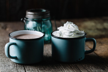 Two cups of hot cocoa on rustic wooden surface