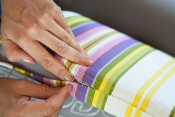A woman sews a bright cloth with a needle. Manual sewing. Needlework.