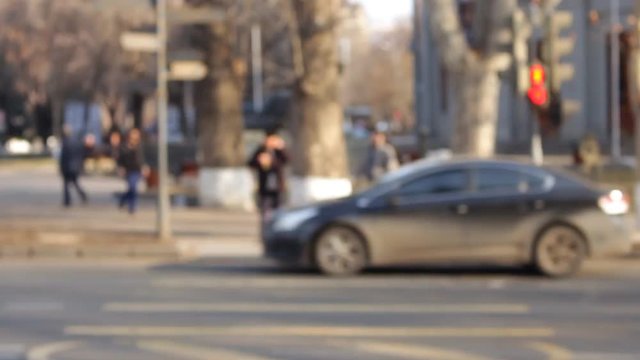 Cars and people out of focus in front of the camera, traffic light, bachground