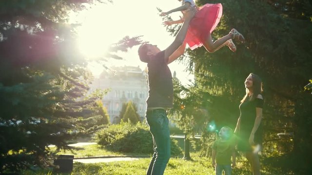 Father throws daughter at sunset - family walking in park - slow-motion