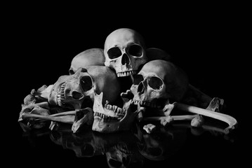 The human skull and pile of bones on black background, Halloween night, Still life style, art.