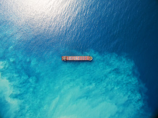 Large bulk carrier ship sailing in open ocean top down aerial shot