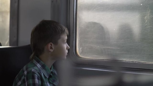 boy rides on a train in the evening looks out the window