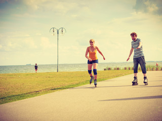 Fototapeta premium Young couple on roller skates riding outdoors