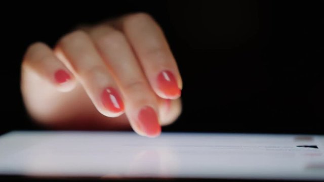 Internet browsing on the tablet. Female fingers scroll text screen, close-up