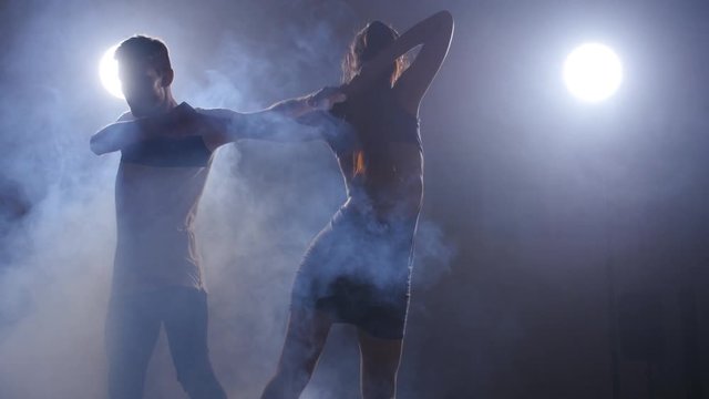 Couple dancing in a dark room in the backlight