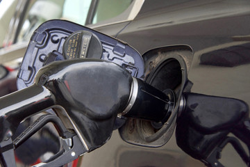 gas pump in tank of dark car pumping fuel