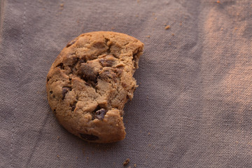 Closeup chocolate chips cookies with bite on brown background