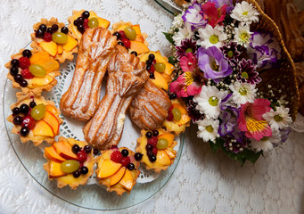 Frozen eclair with candied fruits on a background of a colorful bouquet