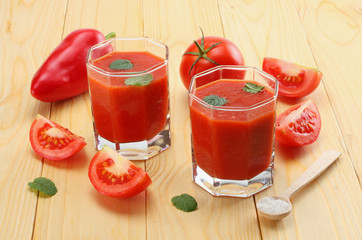 glass of tomato juice with spices on light wooden table