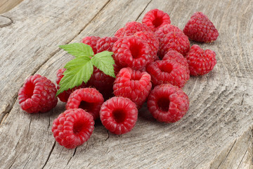 ripe raspberries with green leaf on old wooden table