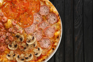 Top view of tasty pizza four seasons on dark wooden background