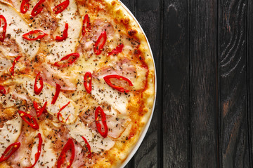 Top view of tasty hot chilli pizza on dark wooden background