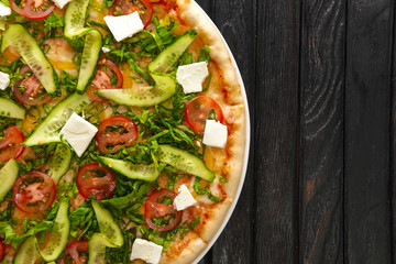 Top view of tasty vegan pizza on dark wooden background