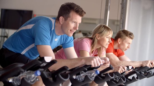 Side view of a spinning class on exercise bikes at a gym