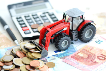 Obraz premium Analyzing financial result in agriculture with tractor pushing a lot of money near office tools