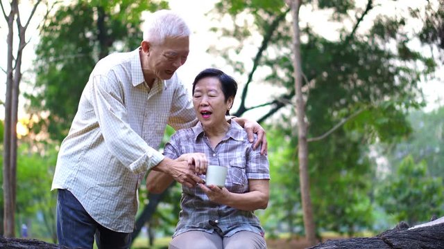 Happy Old Asian senior couple dating at park in the morning. Coffee conversation