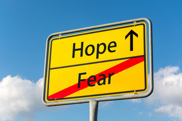 Yellow street sign with Hope ahead leaving Fear behind