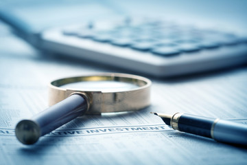 calculator, magnifying glass and pen on financial report