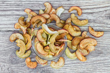 Dried apples in a glass jar and on a wooden background. Healthy vegetarian snack. Closeup, top view