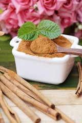 Cinnamon powder and sticks on wood background
