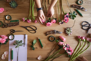 workshop florist. The hand of the girl on the background of the table with flowers. Create floral arrangements.