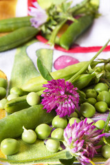 green peas and lilac flowers on tablecloth
