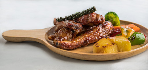 The BBQ pork spareribs on a wooden plate on the white background.