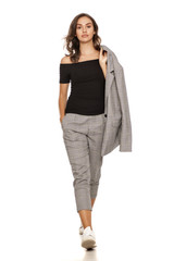young beautiful woman in a jacket, blouse and trousers walking on a white background
