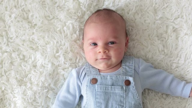 Cute little newborn baby, looking into the camera, happily smiling