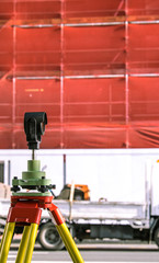 Theodolite building construction surveying equipment with scaffolding and safety netting in background - in Auckland, New Zealand, NZ