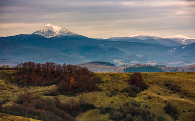 mountain ridge with snowy peak on gloomy day. mysterious late autumn landscape in bad weather with overcast sky