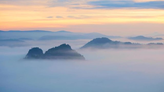 120fps timelapse. Spring misty morning in forest landscape. View around. Majestic peaks cut lighting mist. Deep valley is full of colorful fog and rocky hills are sticking up to Sun. 