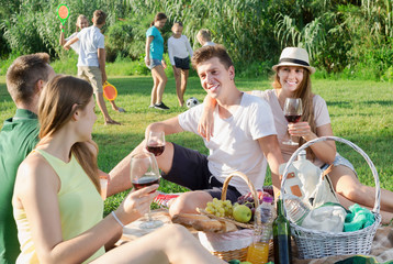 Happy young couples on picnic outdoors with kids