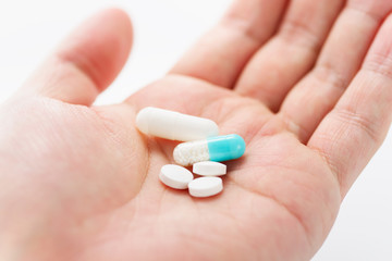 Blue capsule medicines and tablets in male hand. Prescription drugs. Concept image of medication.
