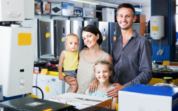 Family of four standing near electronics in household