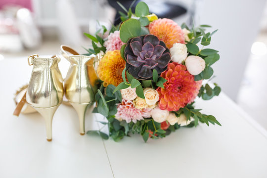 bright wedding bouquet of summer dahlias and roses with women high-heeled shoes
