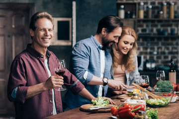 friends drinking wine while cooking dinner