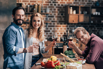 friends drinking wine while cooking dinner