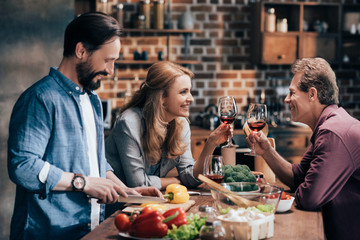 friends drinking wine while cooking dinner