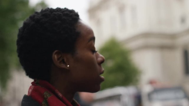 Young black woman waiting to cross the road in the street, in slow motion