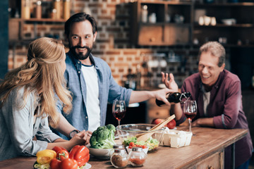 friends drinking wine while cooking dinner