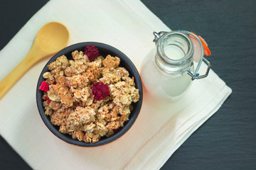 Food breakfast concept Organic Muesli or Granola and milk with napkin on black slate stone plate