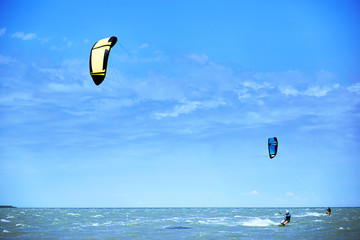 Man riding a kite surfing on the waves in the summer.