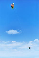 Man riding a kite surfing on the waves in the summer.