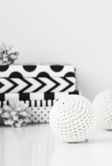 White crochet Christmas balls with modern gifts and pine cones.