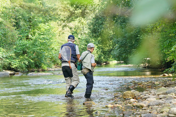 back view of father and son fly-fishing in river